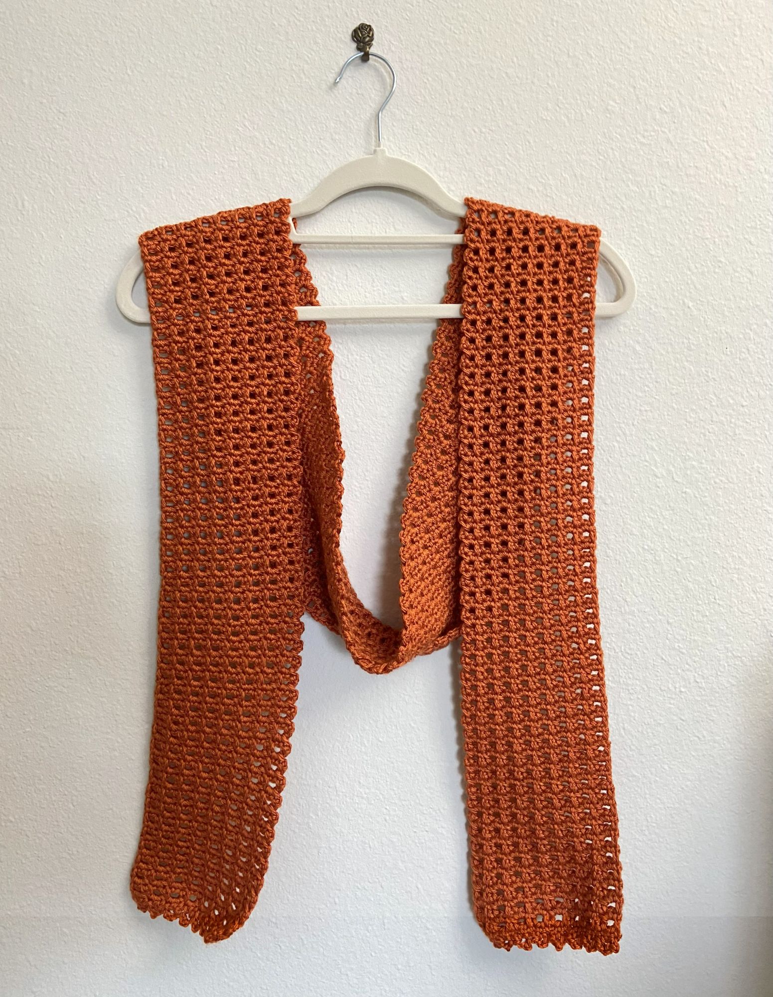 orange crochet scarf on hanger